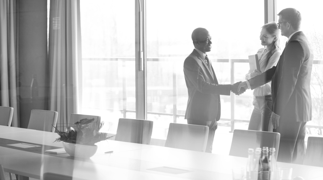 three people in a business conference room shaking hands